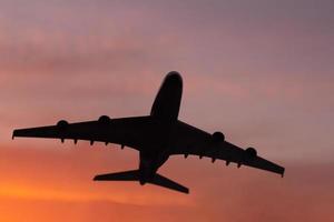 Black silhouette of plane on sunset background photo