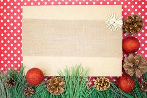 Red shiny balls with cones on green spruce branches on background with polka dots and brown box with burlap. Christmas, New Year. Copy space photo