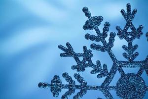 Macro shiny snowflake on blue blurred background. Merry Christmas card. Copy space photo
