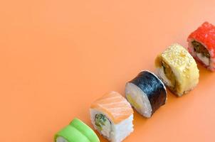 Different types of asian sushi rolls on orange background. Minimalism top view flat lay with Japanese food photo