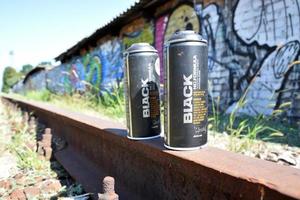 KHARKOV, UKRAINE - MAY 3, 2021 Used Montana black aerosol spray cans against graffiti paintings. MTN or Montana-cans is manufacturer of high pressure spray paint goods photo