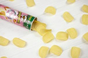 KHARKOV, UKRAINE - MAY 3, 2022 Pringles crab flavour. Cardboard tube can with Pringles potato chips on white table. Pringles is a brand of potato snack chips owned by Kellogg Company photo