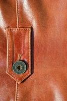 Brown leather texture. Useful as background for any design work. Macro photo of a button on outer clothing made of genuine leather