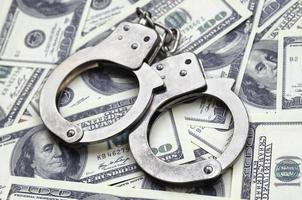 Police handcuffs lie on a lot of dollar bills. The concept of illegal possession of money, illegal transactions with US dollars. Economic Crime photo