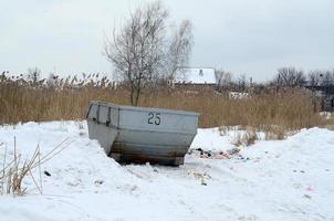 Trash bin at the side of street in winter with lip garbage container winter snow. Metal container for household waste photo
