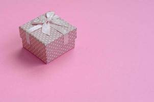 Small pink gift box lie on texture background of fashion pastel pink color paper in minimal concept photo