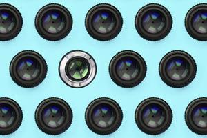 A few camera lenses with a closed aperture lie on texture background of fashion pastel blue color paper photo