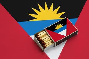 Antigua and Barbuda flag is shown in an open matchbox, which is filled with matches and lies on a large flag photo