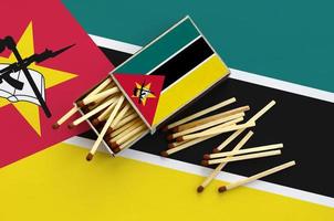 Mozambique flag is shown on an open matchbox, from which several matches fall and lies on a large flag photo