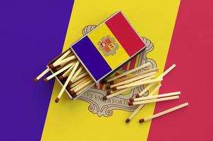 Andorra flag is shown on an open matchbox, from which several matches fall and lies on a large flag photo