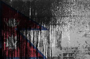 Nepal flag depicted in paint colors on old and dirty oil barrel wall closeup. Textured banner on rough background photo