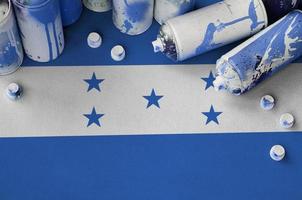 bandera de honduras y pocas latas de aerosol usadas para pintar graffiti. concepto de cultura de arte callejero foto
