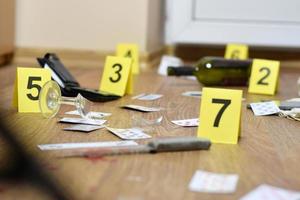 Crime scene investigation - numbering of evidences after the murder in the apartment. A lot of playing cards, wallet and bottle of wine as evidence photo