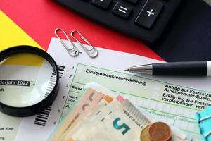 German income tax return form with pen and european euro money bills lies on flag close up. Taxpayers in Germany using euro currency to pay taxes photo