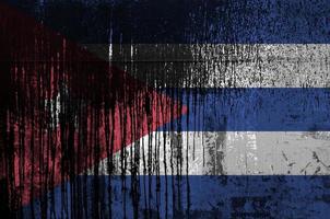 Cuba flag depicted in paint colors on old and dirty oil barrel wall closeup. Textured banner on rough background photo