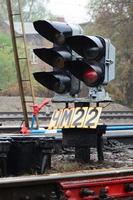 Photo of a fragment of a railway track with a small traffic light in rainy weather