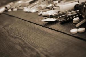 A lot of narcotic substances and devices for the preparation of drugs lie on an old wooden table photo