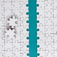 The blue path is laid on the platform of a white folded jigsaw puzzle. The missing elements of the puzzle are stacked nearby. Texture image with space for text photo
