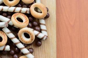 túbulos crujientes, bolas de chocolate y bagels yacen sobre una superficie de madera. mezcla de varios dulces foto