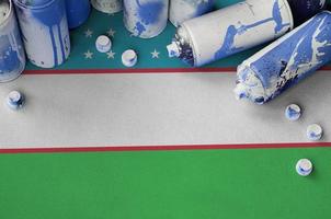 Uzbekistan flag and few used aerosol spray cans for graffiti painting. Street art culture concept photo