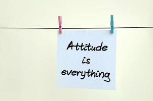 Attitude is everything. Note is written on a white sticker that hangs with a clothespin on a rope on a background of beige wall photo