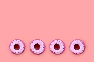 Many small plastic donuts lies on a pastel colorful background. Flat lay minimal pattern. Top view photo