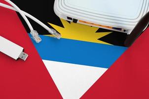 Antigua and Barbuda flag depicted on table with internet rj45 cable, wireless usb wifi adapter and router. Internet connection concept photo