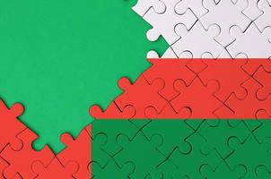 Oman flag is depicted on a completed jigsaw puzzle with free green copy space on the left side photo