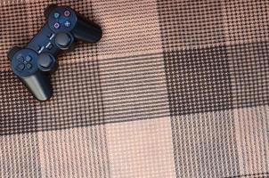 Video game controller lies on a checkered plaid photo