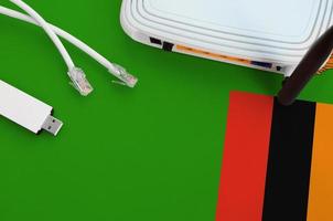 Zambia flag depicted on table with internet rj45 cable, wireless usb wifi adapter and router. Internet connection concept photo