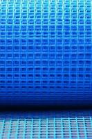 Close-up texture of a blue reinforcing mesh rolled up in a roll. Building resource for reinforcing walls in the process of their warming photo