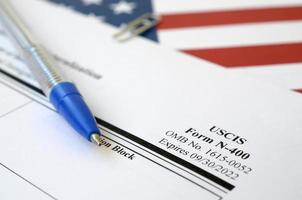 N-400 Application for Naturalization blank form lies on United States flag with blue pen from Department of Homeland Security photo