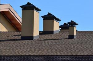 Modern roofing and decoration of chimneys. Flexible bitumen or slate shingles. The absence of corrosion and condensation due to the flexible roof photo