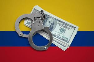 Colombia flag with handcuffs and a bundle of dollars. Currency corruption in the country. Financial crimes photo
