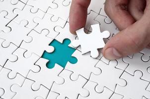 The human hand fills the last missing elements of the surface from the jigsaw puzzle. The concept of the completion of the initiated cases photo