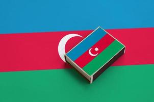 Azerbaijan flag is pictured on a matchbox that lies on a large flag photo