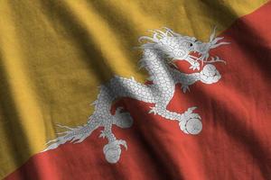 Bhutan flag with big folds waving close up under the studio light indoors. The official symbols and colors in banner photo