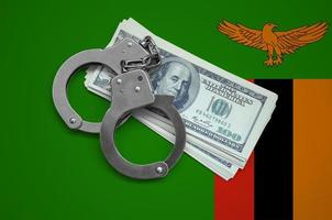 Zambia flag with handcuffs and a bundle of dollars. Currency corruption in the country. Financial crimes photo