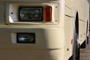 Photo of the hull of a large and long yellow bus. Close-up front view of a passenger vehicle for transportation and tourism