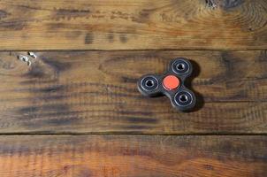 A rare handmade wooden fidget spinner lies on a brown wooden background surface. Trendy stress relieving toy photo