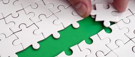 The human hand paves the way to the surface of the jigsaw puzzle, forming a green space. The concept of overcoming the difficulties on the way to success photo