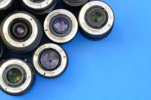 Several photographic lenses lie on a bright blue background. Space for text photo