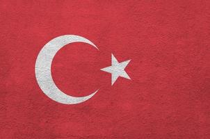 Turkey flag depicted in bright paint colors on old relief plastering wall. Textured banner on rough background photo
