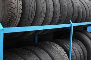 Rack with variety of car tires in automobile store. Many black tires. Tire stack background photo