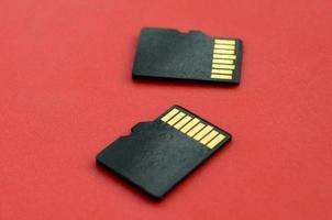 dos pequeñas tarjetas de memoria micro sd se encuentran sobre un fondo rojo. un pequeño y compacto almacén de datos e información foto