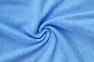 The blanket of furry blue fleece fabric. A background of light blue soft plush fleece material with a lot of relief folds photo