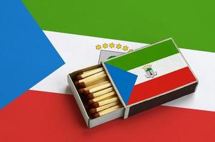 Equatorial Guinea flag is shown in an open matchbox, which is filled with matches and lies on a large flag photo