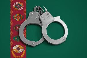 bandera de turkmenistán y esposas policiales. el concepto de observancia de la ley en el país y protección contra el crimen foto