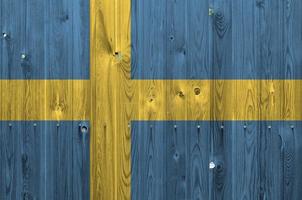 Sweden flag depicted in bright paint colors on old wooden wall. Textured banner on rough background photo