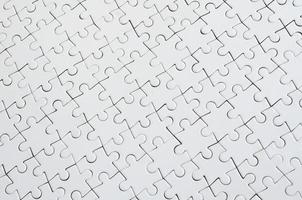 Close up texture of a white jigsaw puzzle in assembled condition. Top view. Many components of a large whole mosaic are united photo